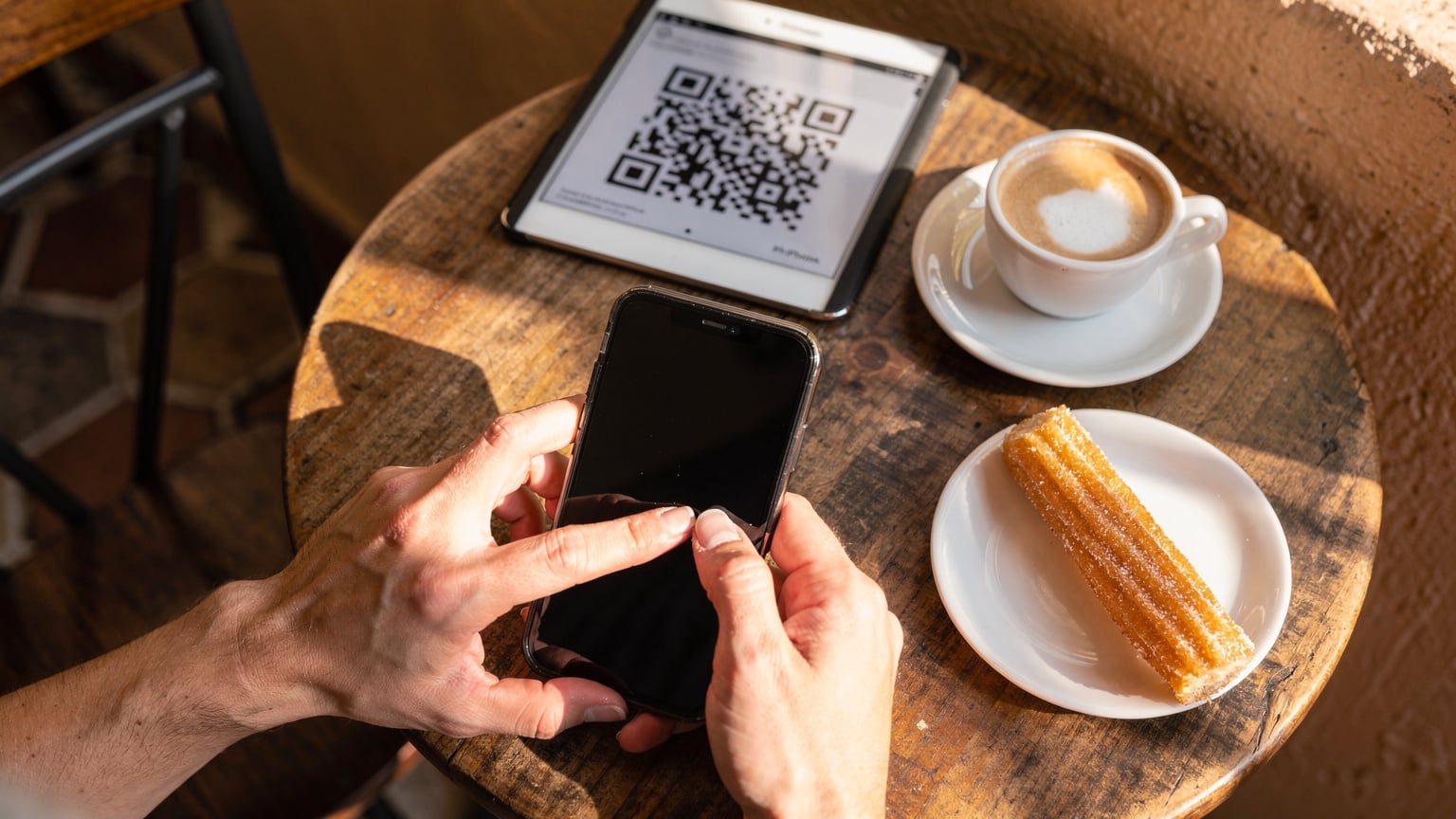 Un viajero activa su eSIM en un café de Madrid, mientras su café con leche se enfría, demostrando la rapidez del proceso.