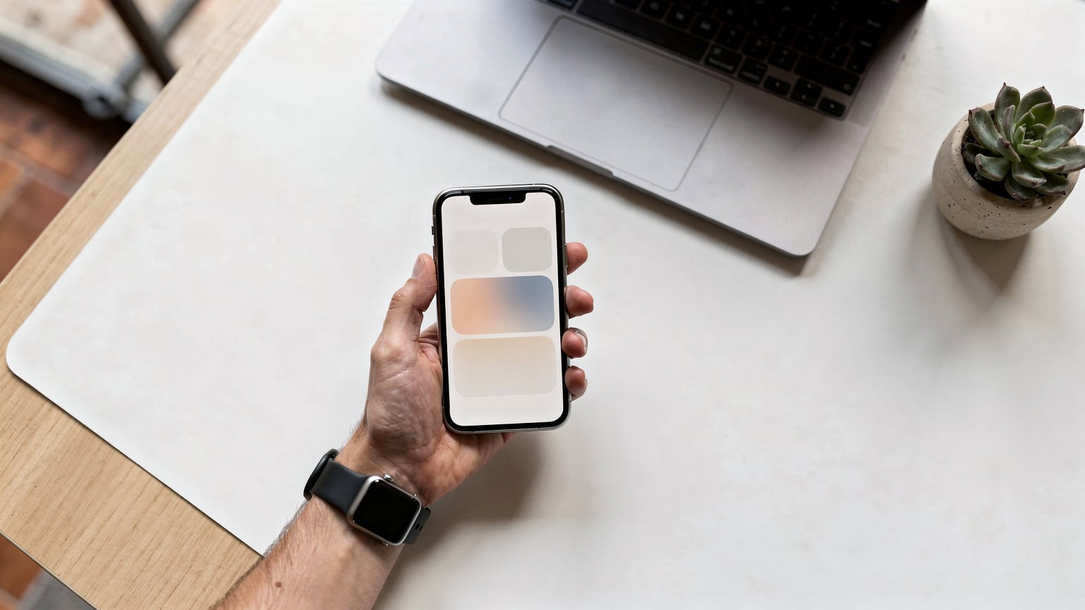 Una mano sostiene un iPhone y un Apple Watch, ambos con la interfaz de activación de eSIM, en el contexto de un escritorio de trabajo minimalista en un co-working de Barcelona.