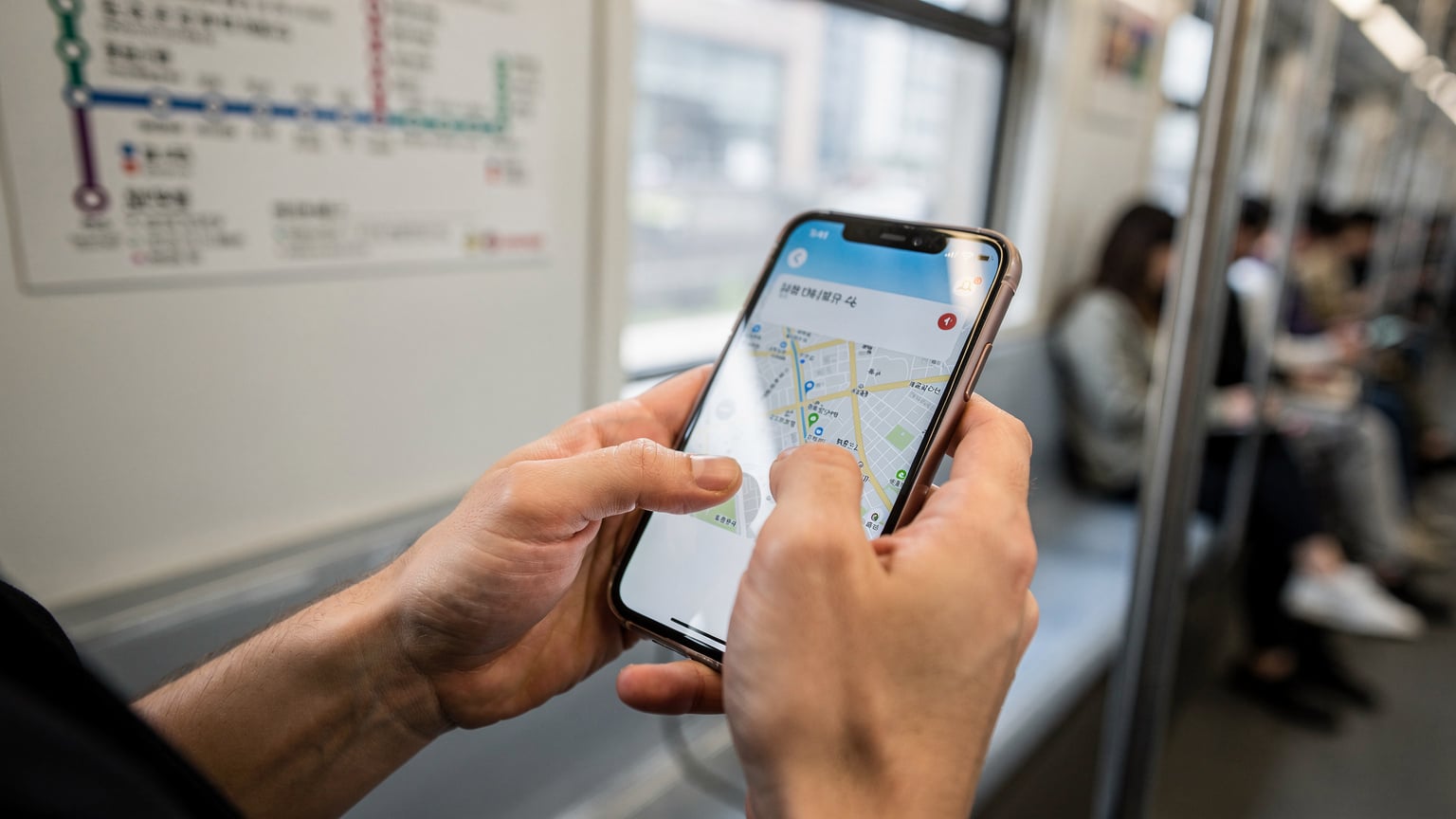 ソウルの地下鉄内で、スマートフォンを操作し、地図アプリで次の目的地を確認している旅行者の手元。