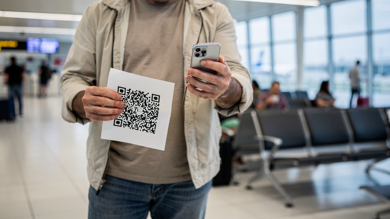 Muž skenuje QR kód pro aktivaci eSIM na letišti v Heraklionu na Krétě.