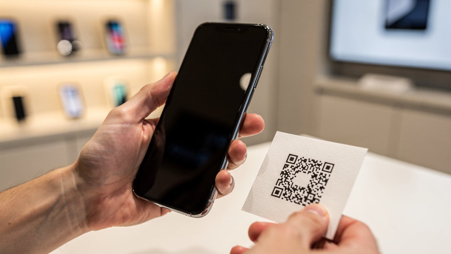 A close-up shot of hands holding a smartphone, scanning a QR code for eSIM activation, with a blurred background of a modern retail store.