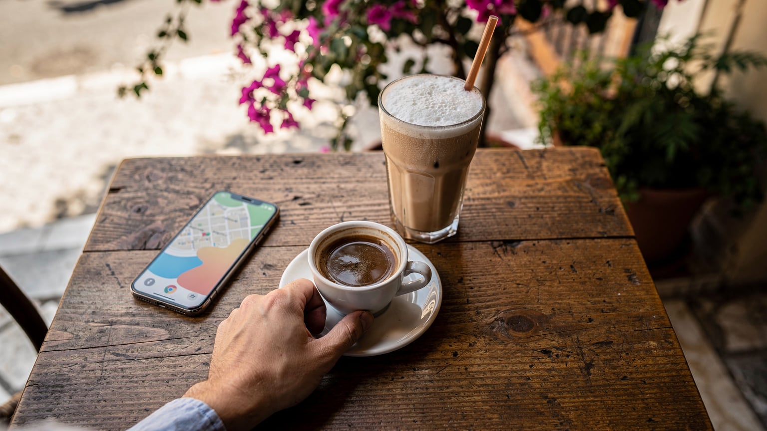 A person sips Greek coffee at a traditional kafenio in a quiet Athens neighbourhood, with a phone on the table displaying a map, blending local culture with modern connectivity.