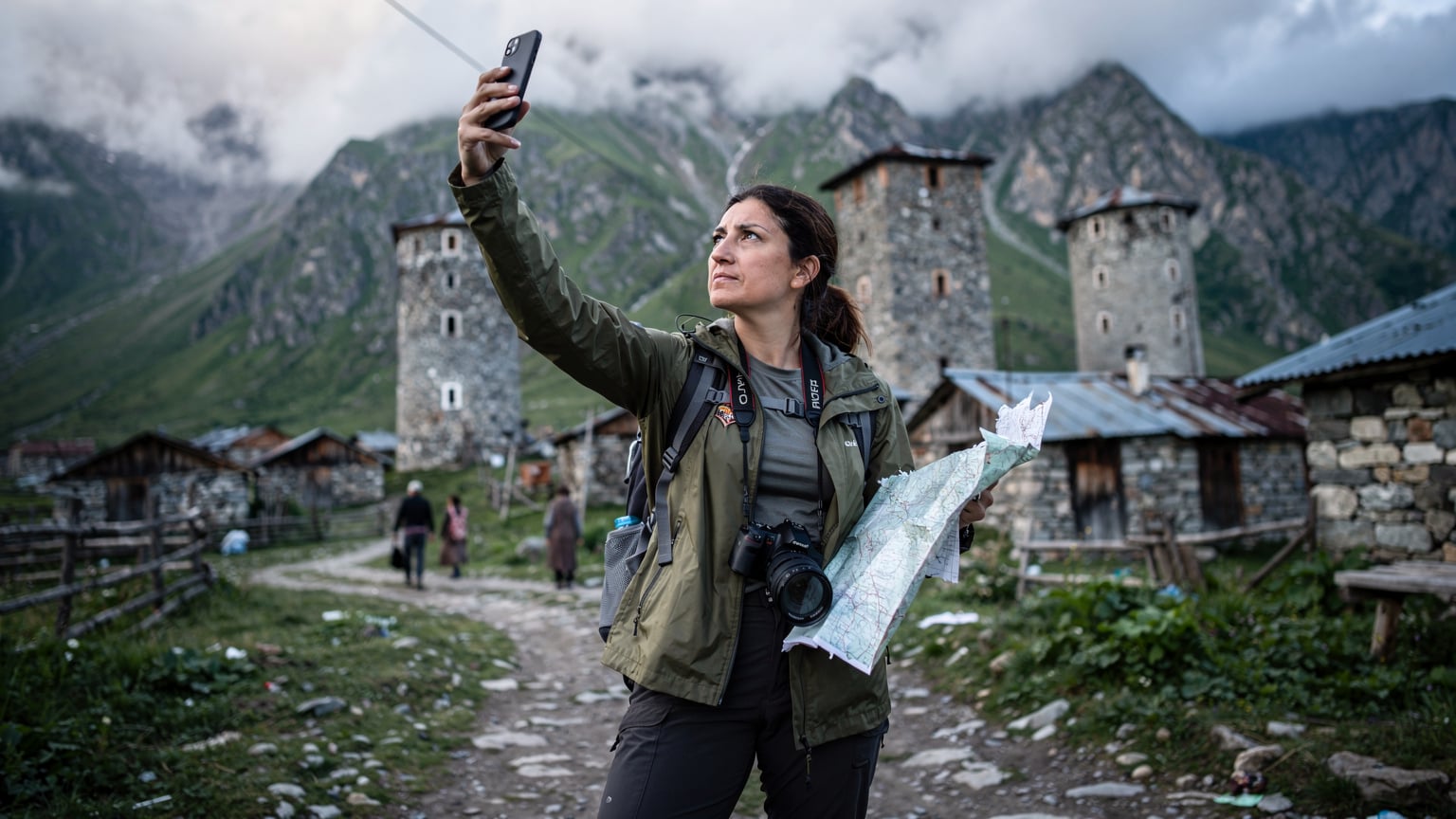 Ayça Demirkan, elinde telefonunu tutarak bir haritaya bakıyor ve uzak bir Gürcü köyünde sinyal çekmeyen bir alanda zorluk yaşıyor.