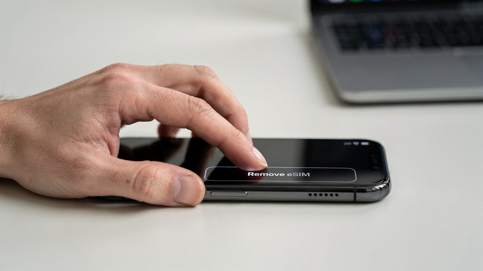 एक iPhone पर 'Remove eSIM' विकल्प पर टैप करता हुआ हाथ, जो eSIM सेटिंग्स मेनू में है।
