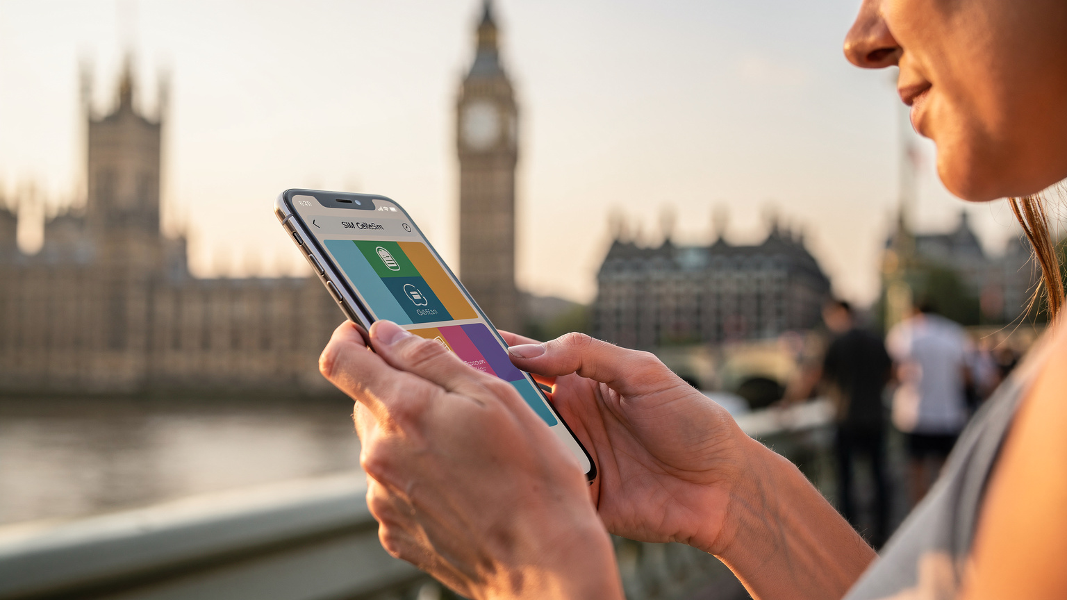 Bir annenin elinde tuttuğu akıllı telefonda Cellesim uygulamasının veya bir eSIM profilinin kurulum aşamasını gösteren ekran görüntüsü, arka planda Big Ben veya Westminster Sarayı'nın silüeti.