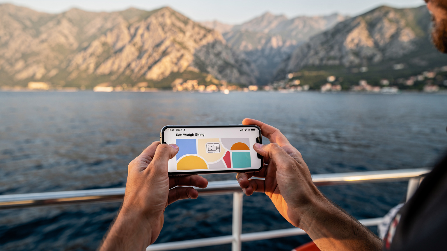 Ein Reisender hält ein Smartphone mit einer geöffneten eSIM-App in der Hand, während er auf einer Fähre über die Adria fährt, mit der Küste Montenegros im Hintergrund.