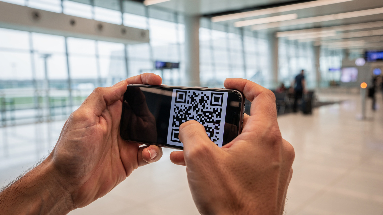 Un călător folosește un telefon iPhone pentru a scana un cod QR pentru eSIM, într-un terminal modern al Aeroportului Internațional Henri Coandă, București.