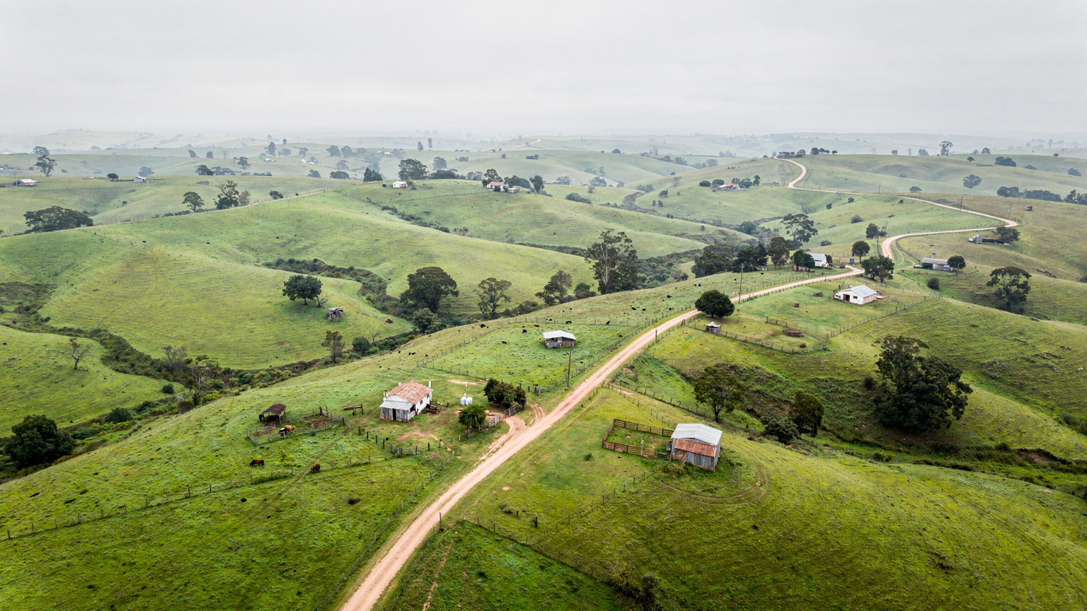 Vista aérea de un paisaje rural en Uruguay, con campos verdes y caminos de tierra, mostrando la posible escasez de infraestructura de telecomunicaciones.