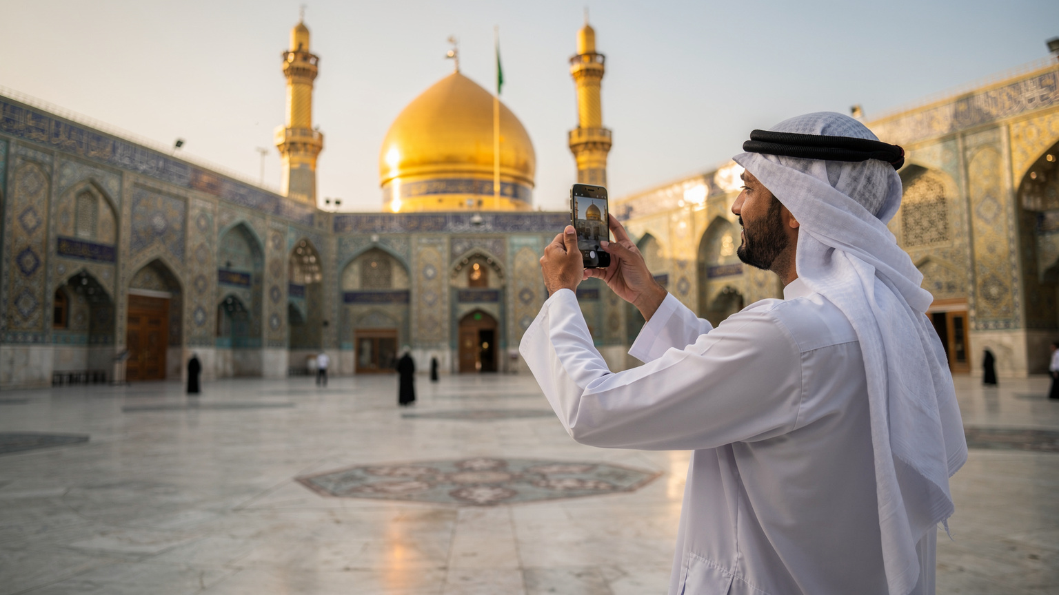 زائر يلتقط صورة بانورامية لهاتف ذكي في صحن الإمام علي في النجف الأشرف، مع تفاصيل العمارة الإسلامية المحيطة.
