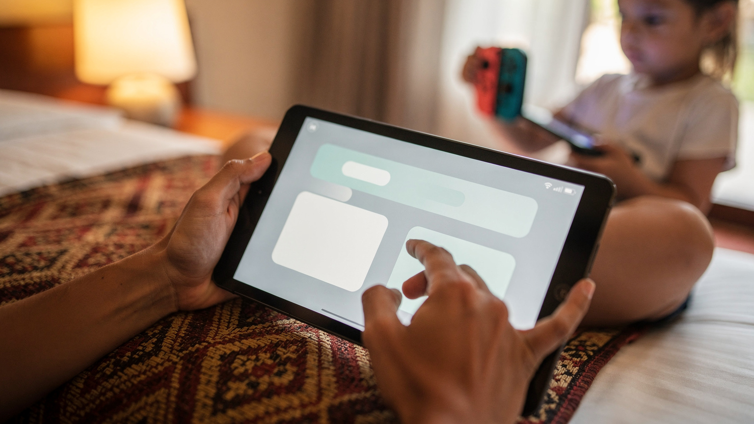 Close-up of a parent's hand adjusting screen time settings on an iPad, with a child's hand holding a Nintendo Switch Lite in the blurred background, set in a cozy hotel room in Bali.