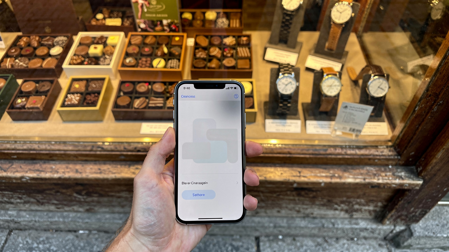 O mână ține un smartphone cu ecranul pe o pagină de setări eSIM, în fața unei vitrine de magazin elvețian, cu ciocolată și ceasuri expuse.