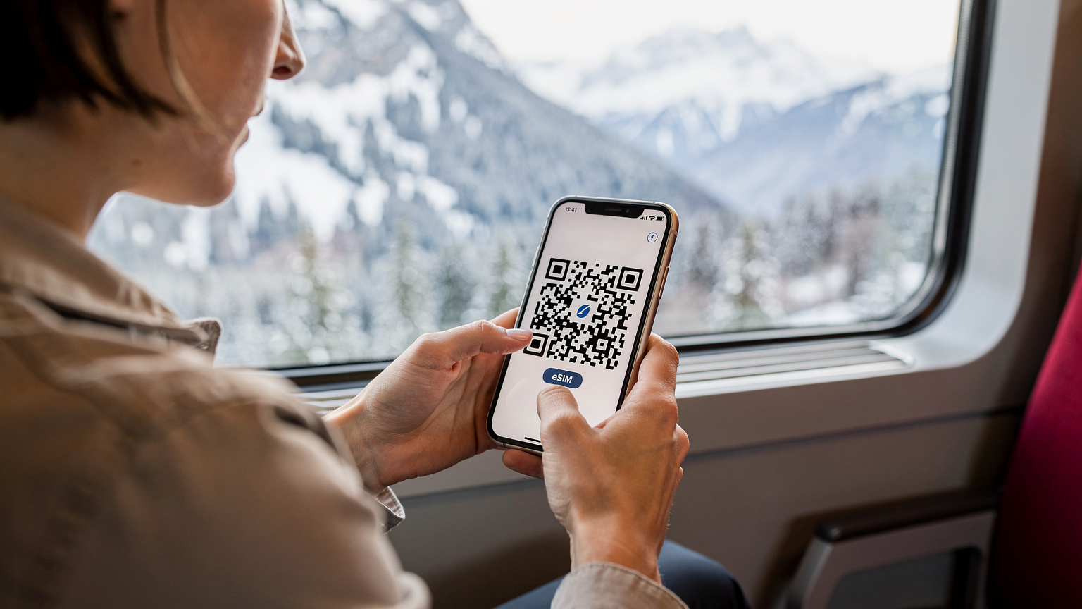 O călătoare își activează eSIM-ul pe un iPhone într-un tren elvețian modern, privind pe fereastră peisajul montan.