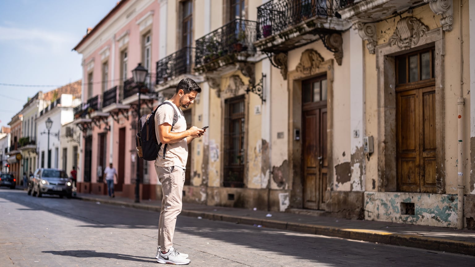 Un viajero revisa su teléfono frente a edificios históricos en Asunción, Paraguay.