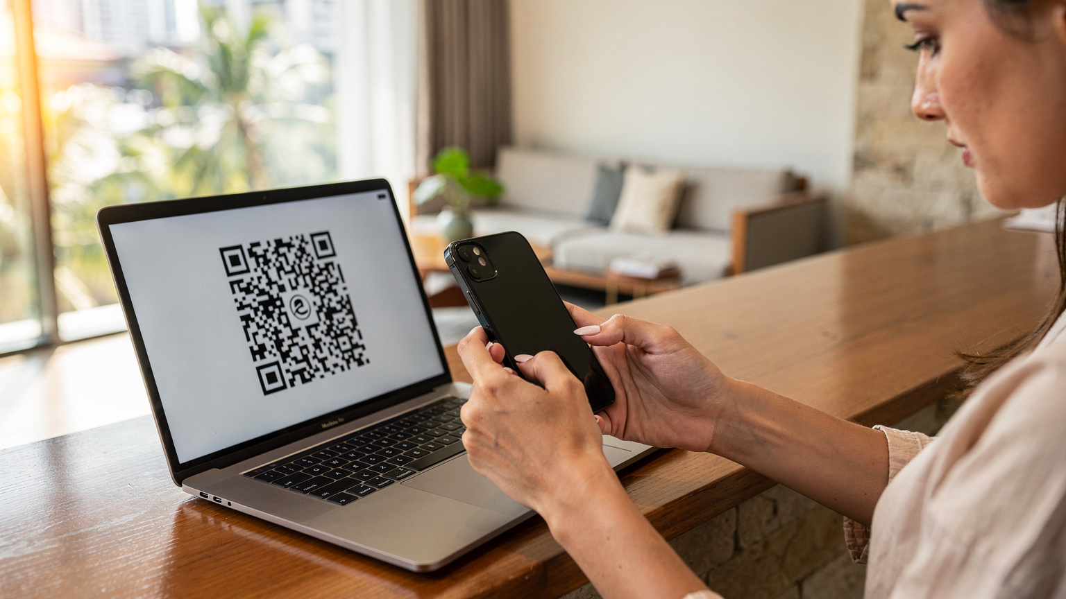 Một phụ nữ đang quét mã QR trên màn hình laptop bằng iPhone của mình tại sảnh khách sạn ở Bangkok.