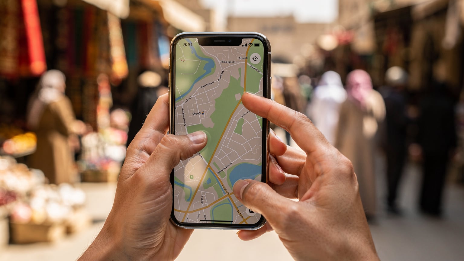 امرأة تتصفح خريطة رقمية على هاتفها وهي تسير في سوق شعبي في بغداد.