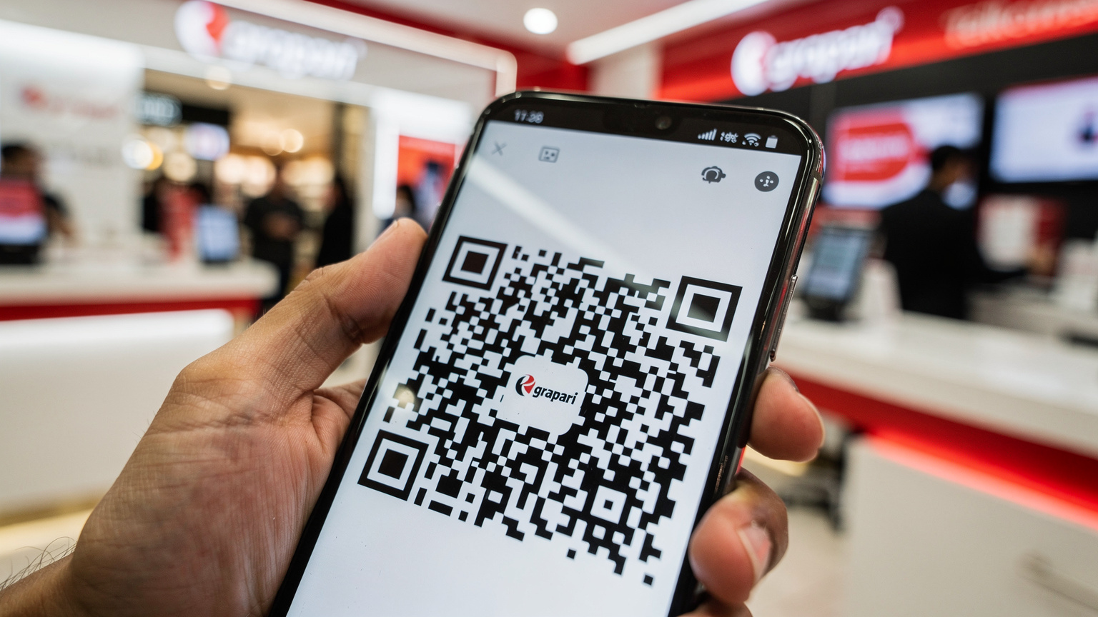 Tampilan layar smartphone yang menunjukkan proses aktivasi eSIM, dengan fokus pada kode QR yang siap dipindai dan tangan memegang ponsel di latar belakang sebuah gerai Grapari Telkomsel yang modern dan terang di pusat perbelanjaan Jakarta.