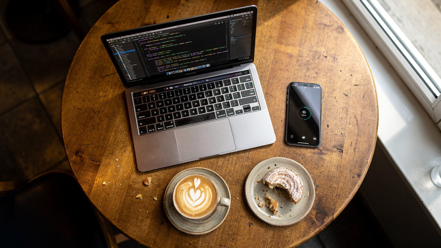 Digitální nomádka pracuje na svém notebooku v útulné kavárně v karlínské čtvrti v Praze, zatímco její smartphone leží vedle ní, připojený k internetu přes eSIM.