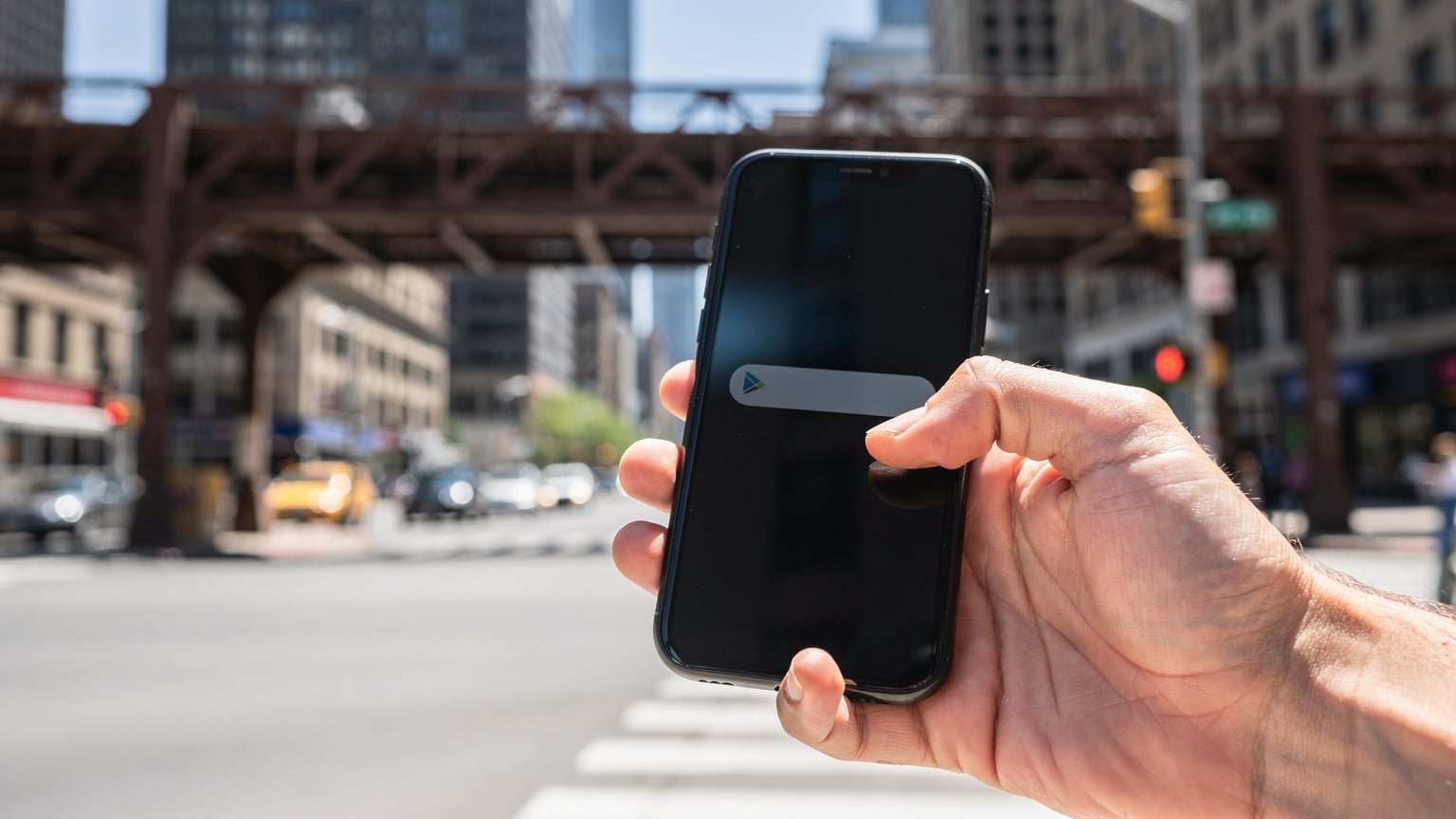 Nærbilde av en hånd som holder en smarttelefon, med fokus på en notifikasjon om lavt dataforbruk på skjermen, i et lys av et travelt gatehjørne i Chicago.
