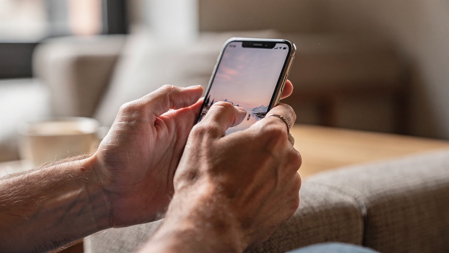 Un primo piano delle mani di una persona che tiene uno smartphone e lo scorre, con il dito che sfiora lo schermo per interagire con un'app di viaggio.