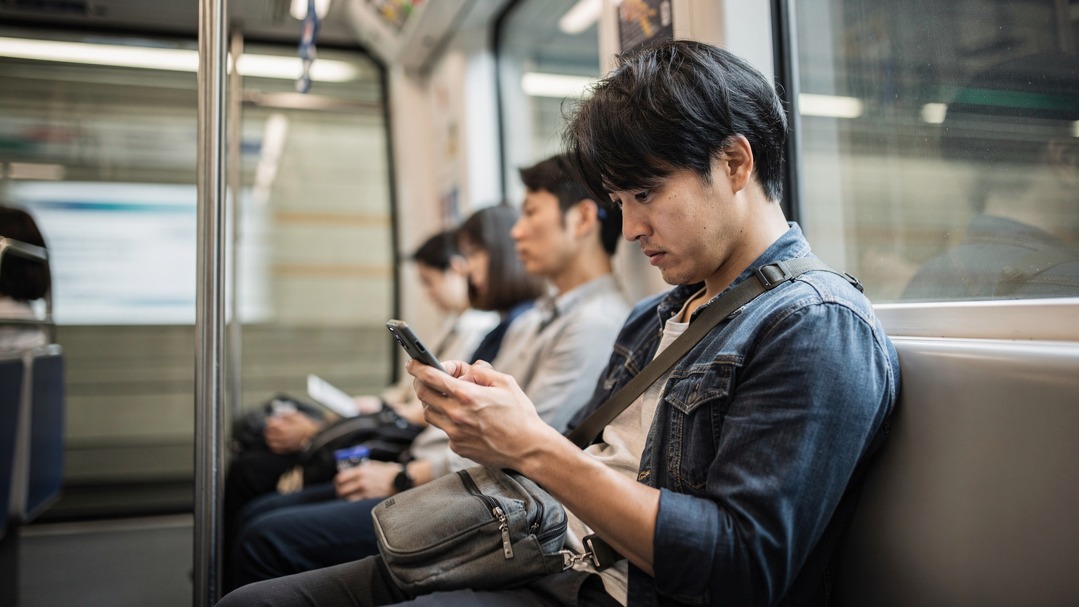 ソウルの地下鉄車内で、スマートフォンを凝視しながらLINE電話の接続不良に悩む日本人旅行者。電波状況が悪く、少し困惑した表情。