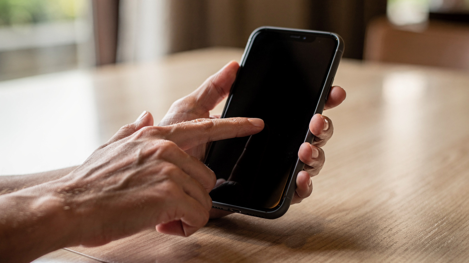 Close-up of human hands holding a smartphone, with a finger gently tapping the screen to confirm a digital setting, showing no discernible on-screen text or logos.