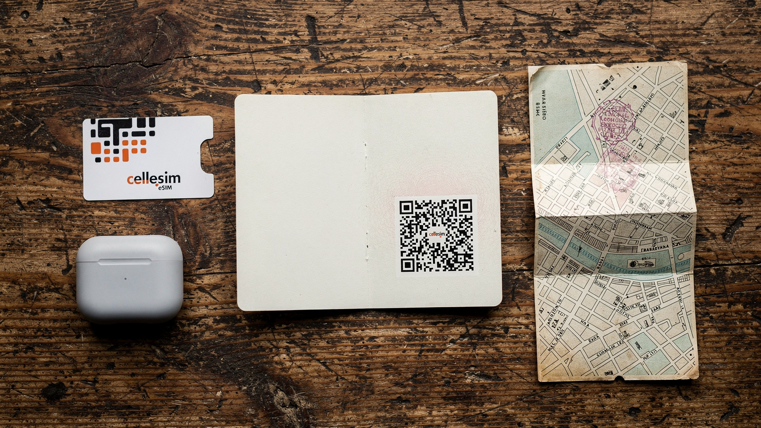 An editorial overhead flat-lay shot on a rustic wooden table, featuring a passport, a Cellesim eSIM QR code on a small, elegantly designed card, a pair of sleek wireless earbuds, and a vintage-style map snippet of Barcelona's El Born district.