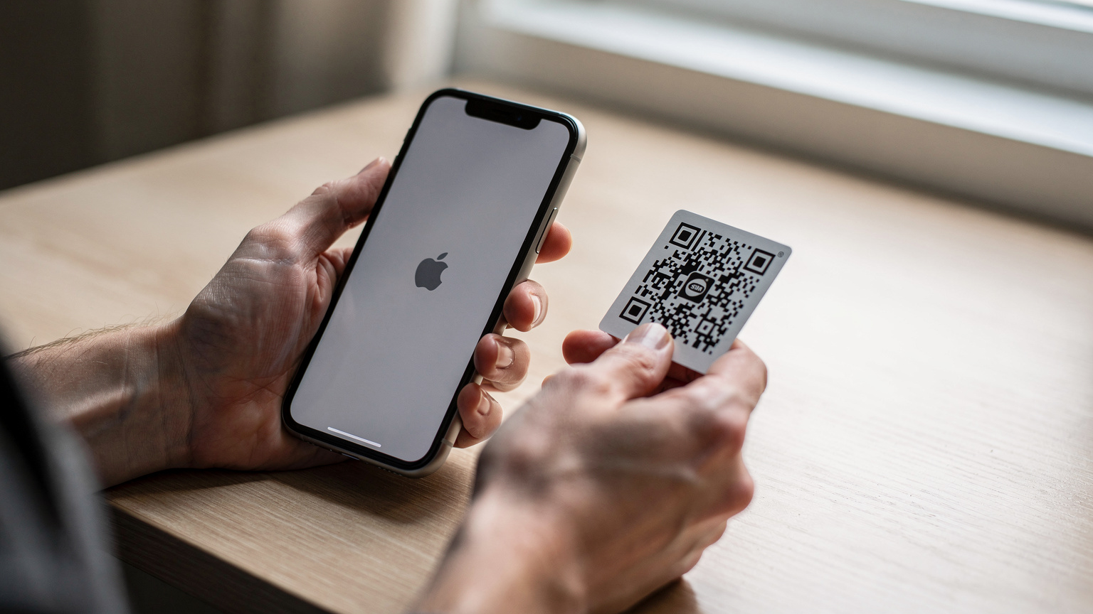 Nahaufnahme von Händen, die ein iPhone 11 halten, während eine weitere Hand einen QR-Code auf einem Papier scannt, um eine eSIM zu aktivieren. Der Fokus liegt auf der Interaktion der Hände und des Geräts.