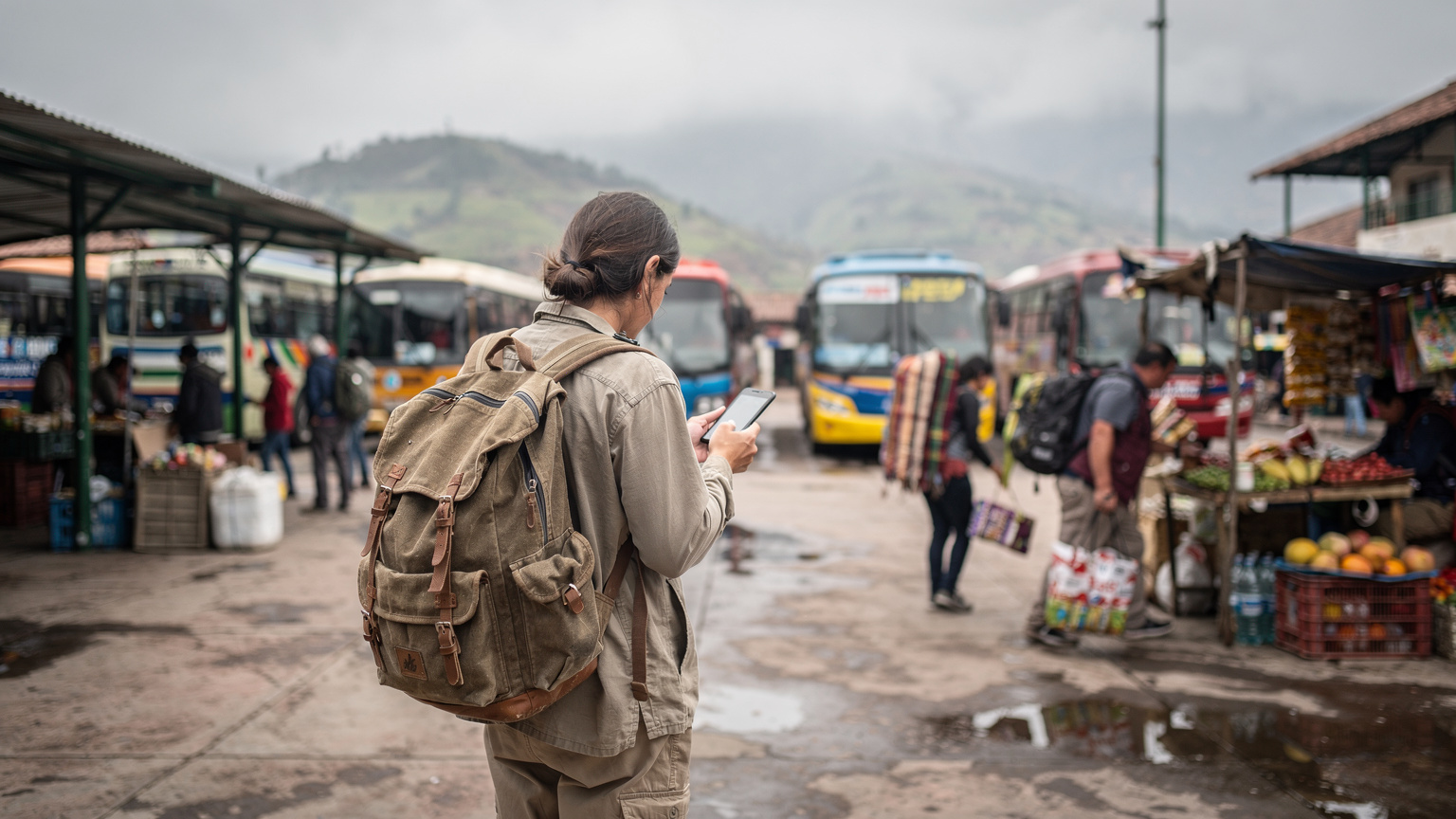 A solo traveler, seen from behind, standing at a bustling local bus terminal in Cusco, Peru, checking their phone for directions before boarding.