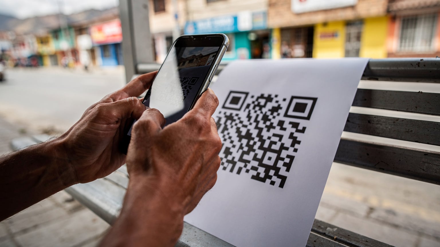 Bir gezginin eli, La Paz'daki bir otobüs durağının bekleme salonunda, telefonunun ekranında bir eSIM QR kodunu tararken gösteriliyor.