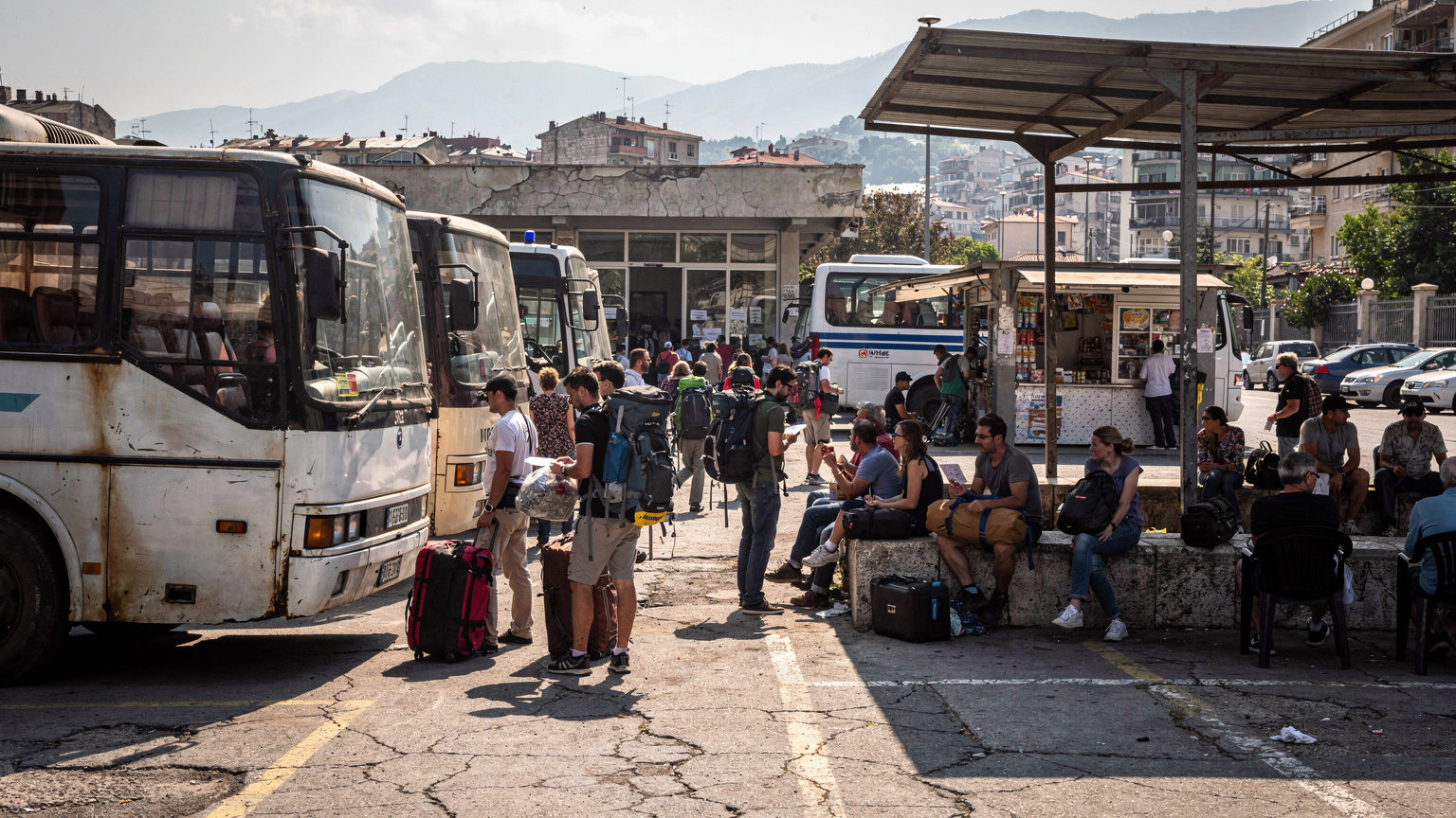 Ein überfüllter Busbahnhof in Tirana, Albanien, mit Menschen, die auf ihre Busse warten, und dem geschäftigen Treiben des Alltags.