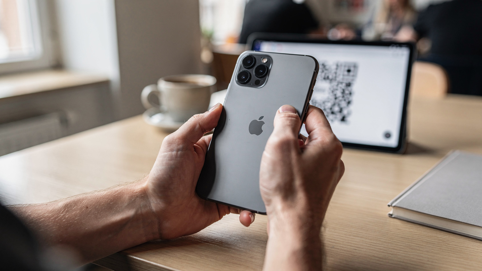 Nahaufnahme von Händen, die ein iPhone 11 Pro halten, und ein anderer Bildschirm zeigt einen eSIM-QR-Code, der gerade gescannt wird.