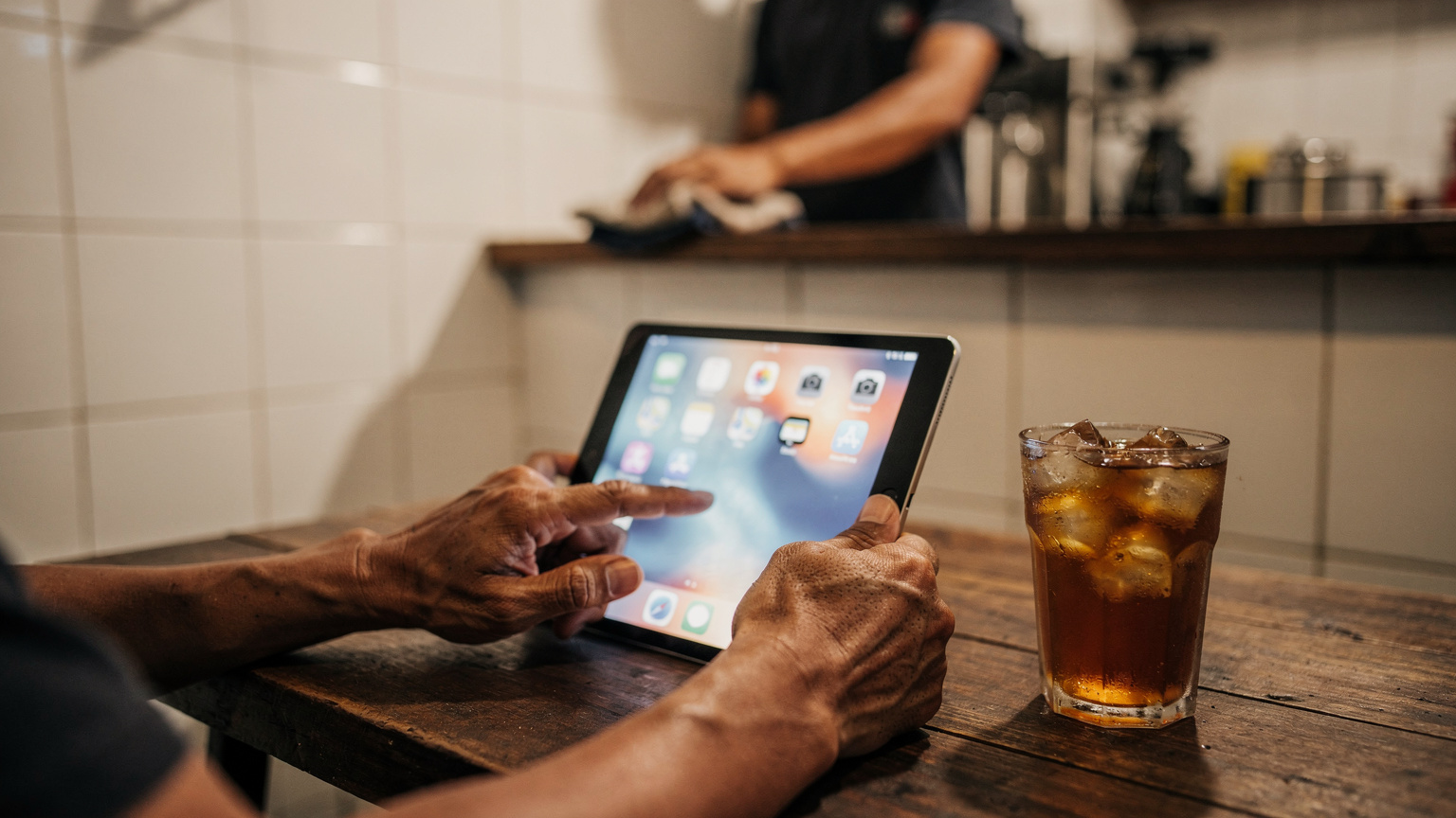 Tangan seorang ayah memegang iPad mini di pangkuannya, mengatur pengaturan jaringan di dalam kafe dekat Stasiun Kota, Jakarta Barat