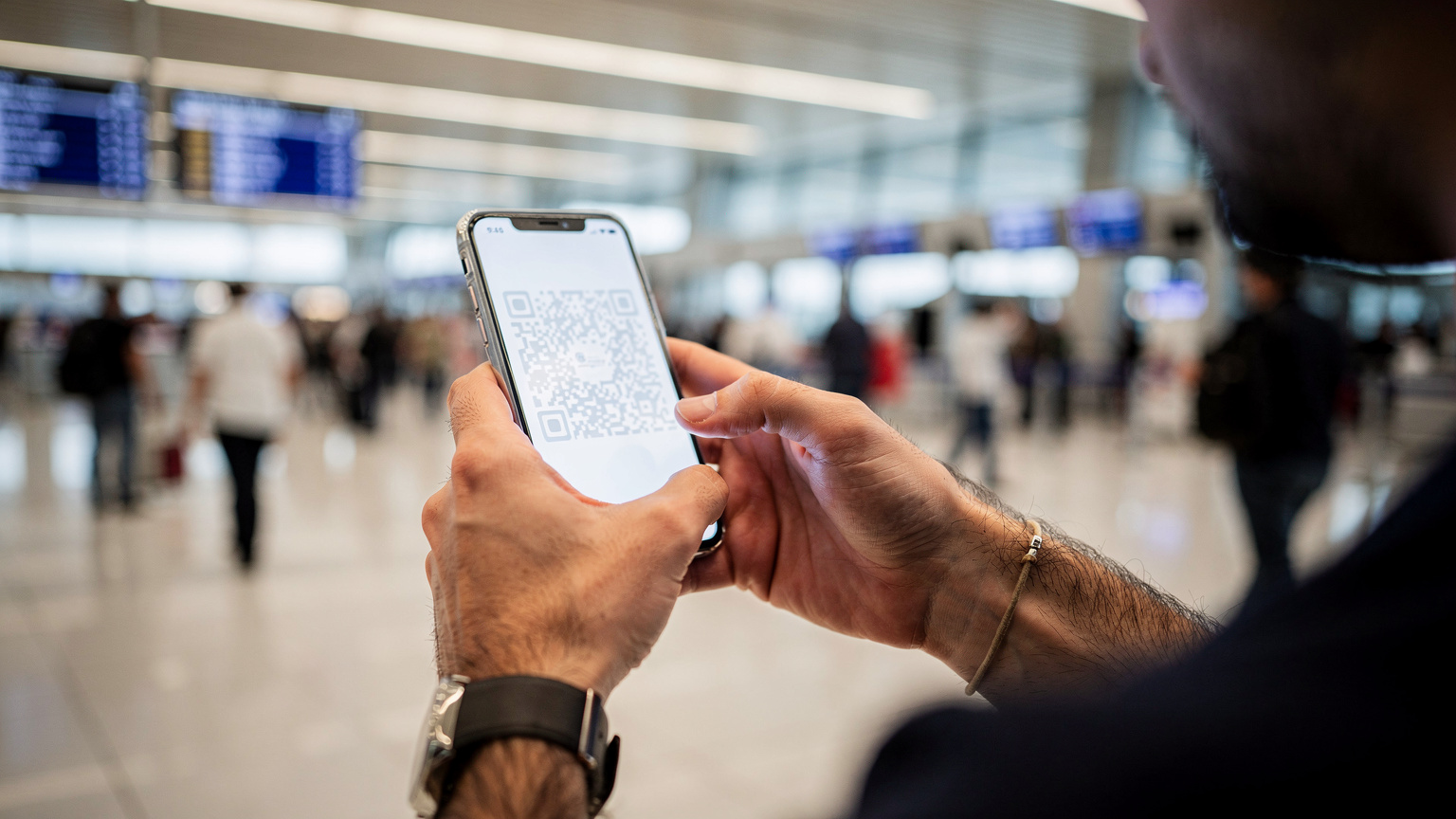 İstanbul Havalimanı dış hatlar terminalinde, pasaport kontrolünden yeni geçmiş bir Türk gezginin, akıllı telefonundaki eSIM kurulum QR kodunu dikkatle tararken çekilmiş yakın plan fotoğrafı. Arka planda hareketli terminalin bulanık ışıkları görünüyor.
