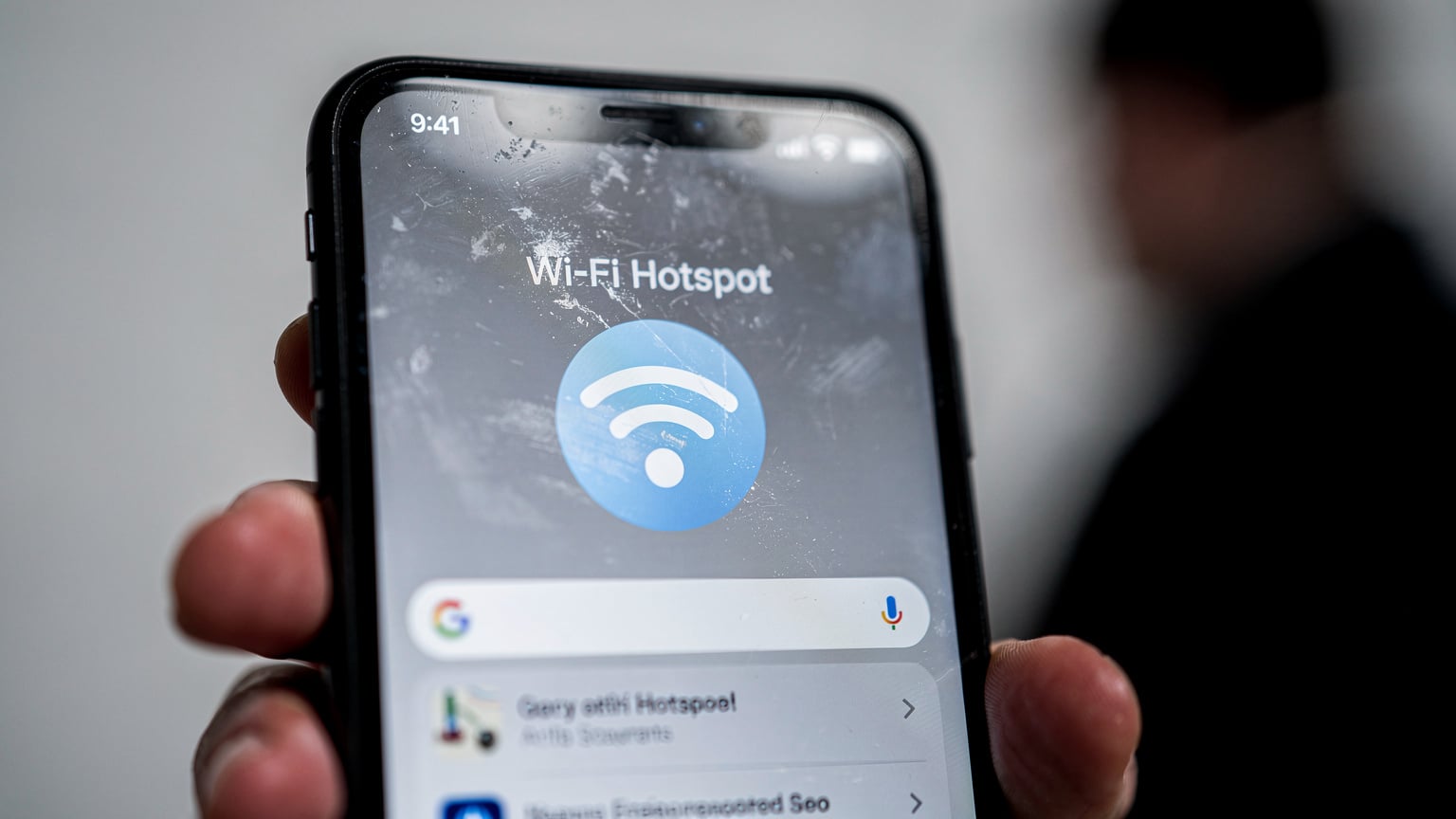 Osoba udostępniająca internet z telefonu przez hotspot, z ikoną Wi-Fi na ekranie