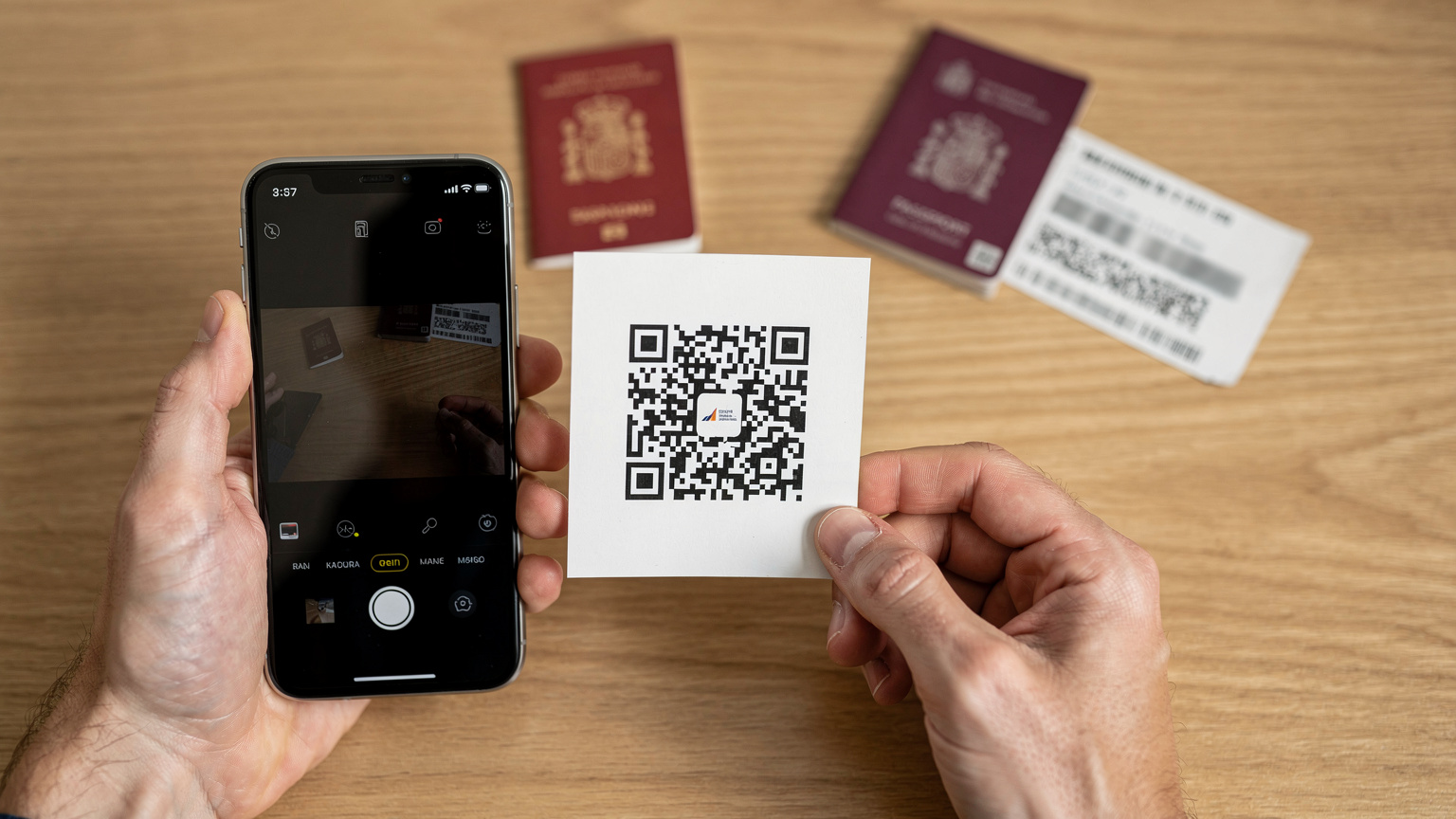 Manos de un viajero sosteniendo un smartphone, acercando el código QR de una eSIM a la cámara para su activación, con un fondo suavemente desenfocado de un pasaporte y un billete de avión, en un escritorio.