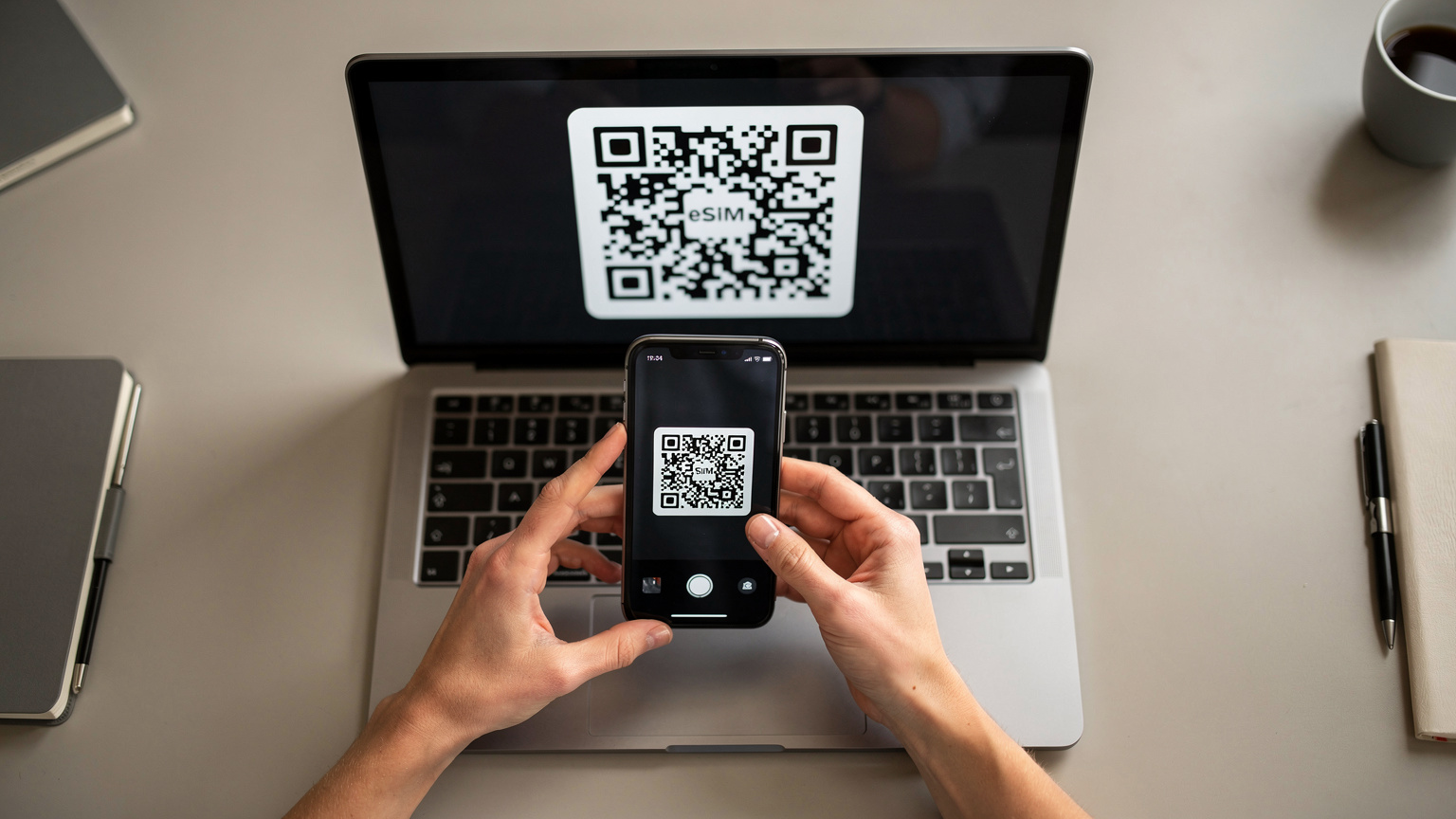 Die Hände einer Frau scannen einen QR-Code auf dem Bildschirm eines Laptops mit der Kamera ihres Smartphones, um eine eSIM zu aktivieren.