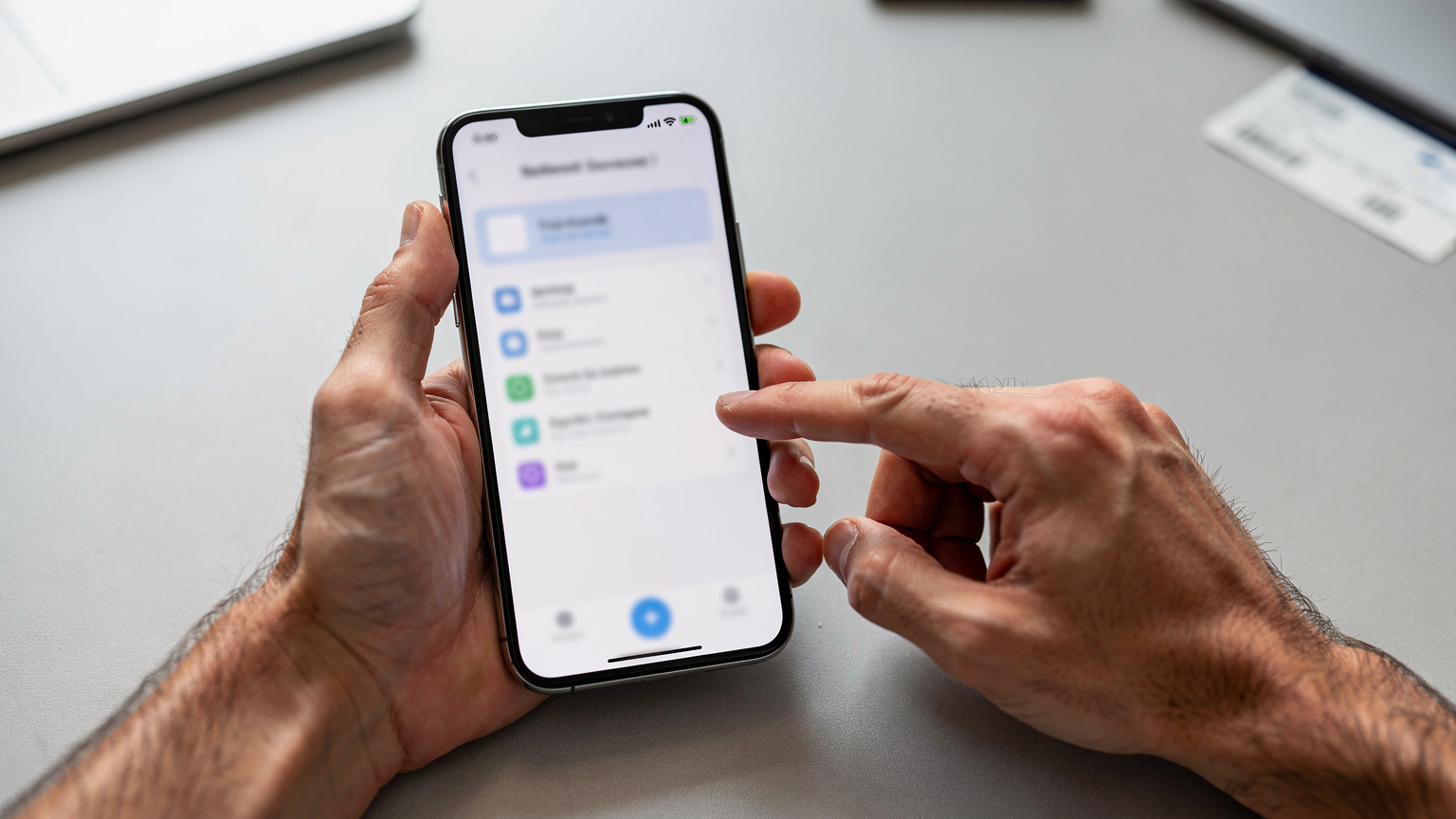 A close-up of hands interacting with a smartphone screen, showing the process of switching between available network profiles on a multi-carrier eSIM, demonstrating user control.