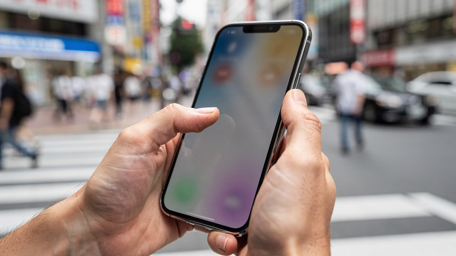 Japonya'nın yoğun bir cadde üzerinde, bir elin iPhone 17'yi tutarak eSIM ayarlarını kontrol ettiği yakın çekim.