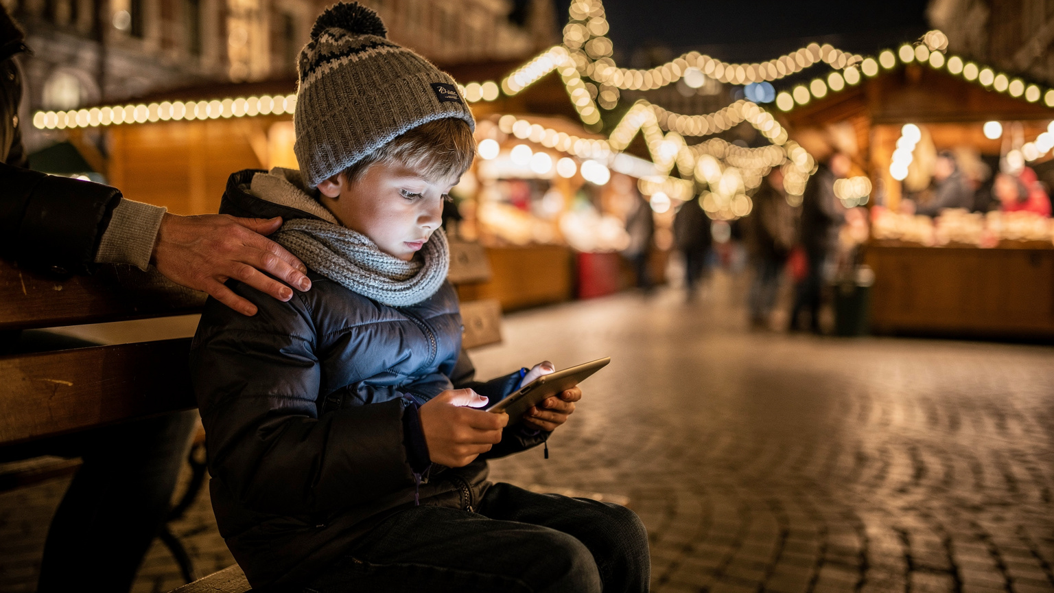 A child, around 8 years old, is engrossed in a game on an iPad, sitting on a bench at the edge of a bustling Amsterdam Christmas market, with a parent's hand gently resting on their shoulder.