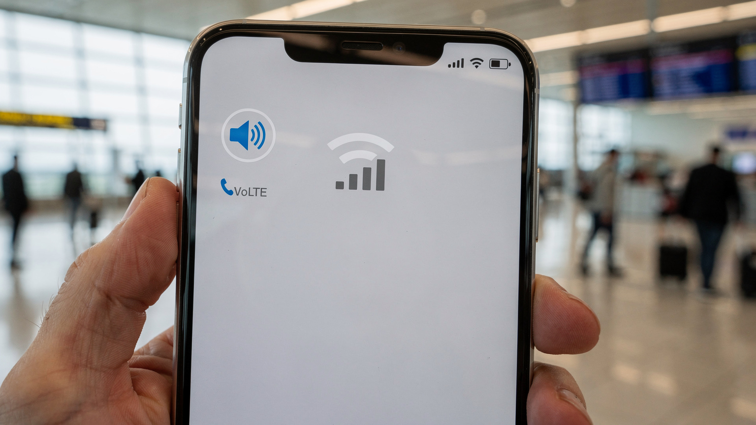 A close-up of a smartphone screen displaying a successful VoLTE call icon, held by a person in a busy airport terminal, underscoring the reliability of voice services with an eSIM.