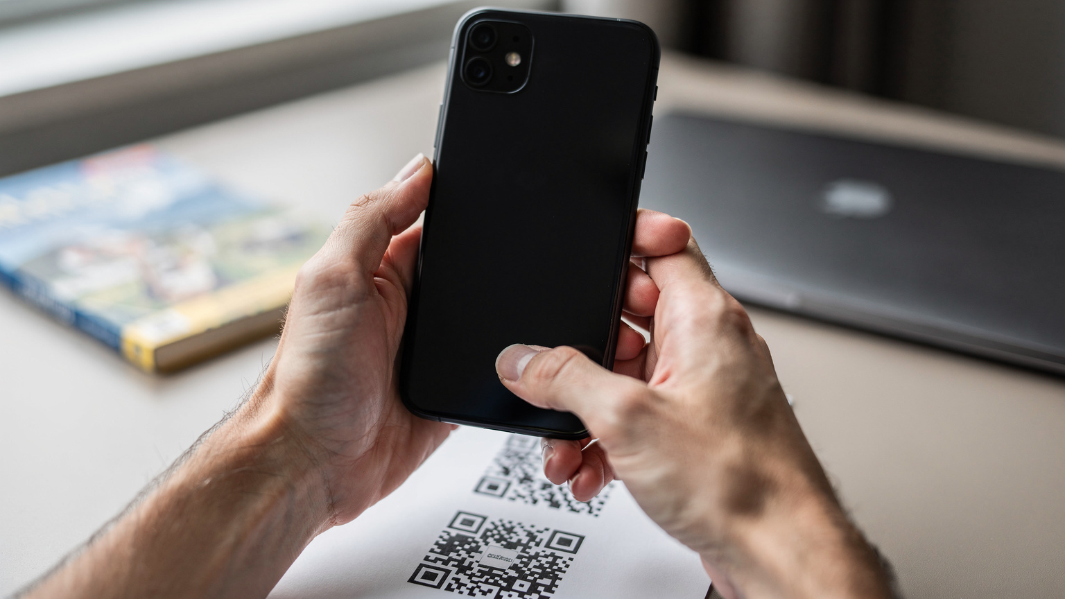 Hands holding a smartphone over a printed QR code, indicating the process of eSIM activation for travel.