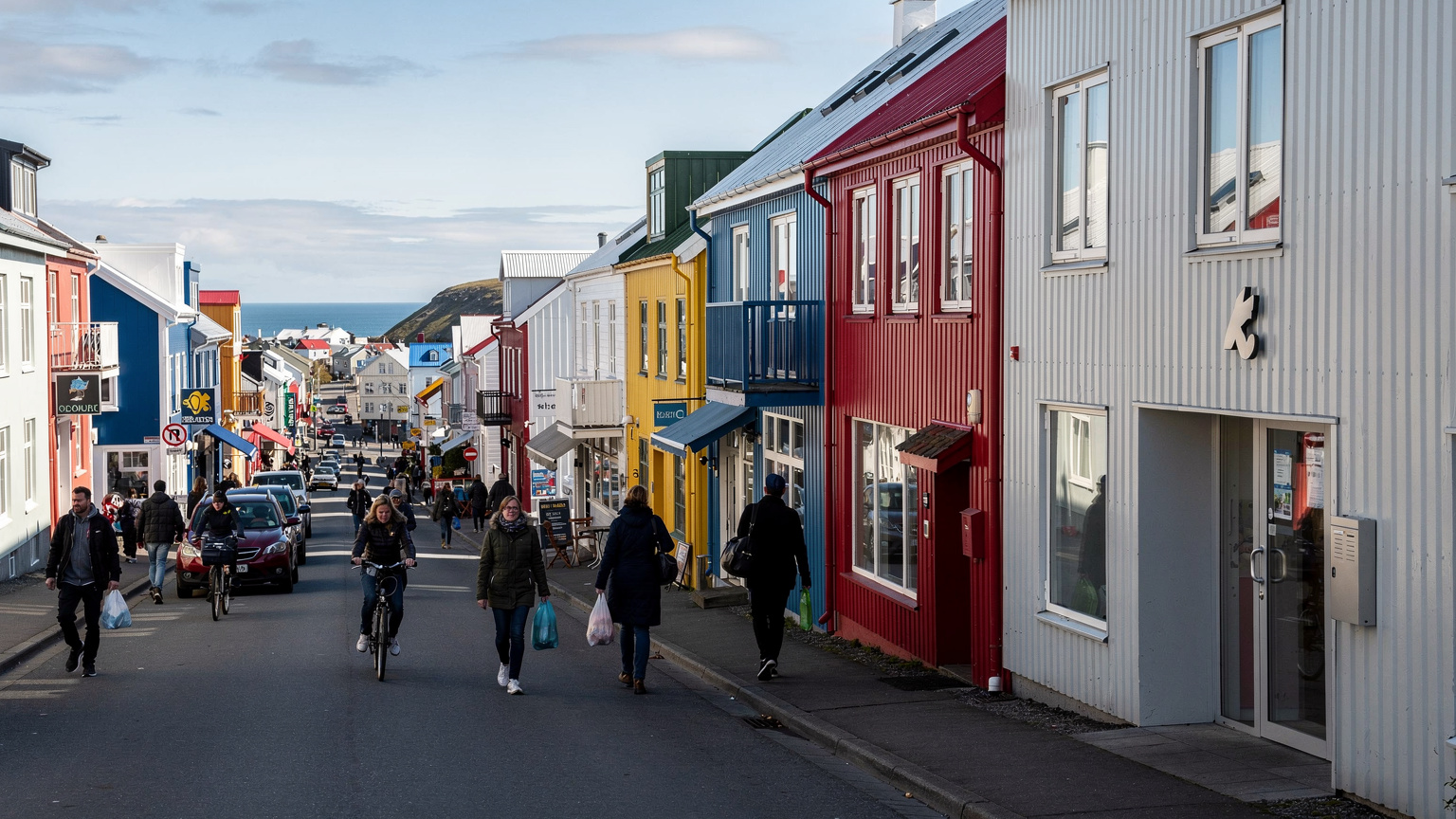 En travel gate i Reykjavik sentrum med fargerike bygninger og en diskret inngang til et co-working space, der folk spaserer forbi.