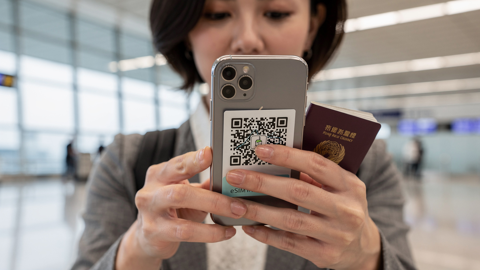 一名旅客在香港國際機場的到達大廳,手持護照和智能手機,正在掃描Cellesim eSIM的二維碼,準備激活網絡服務。