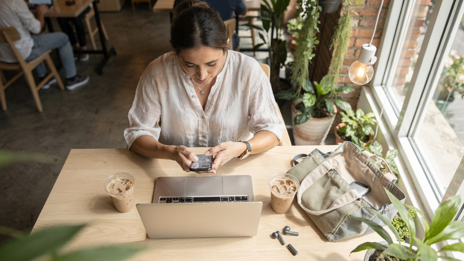 Chiang Mai'de bir co-working kafede, laptopu ve kahvesiyle oturan bir dijital göçebe, telefonundan eSIM veri kullanımını kontrol ediyor.
