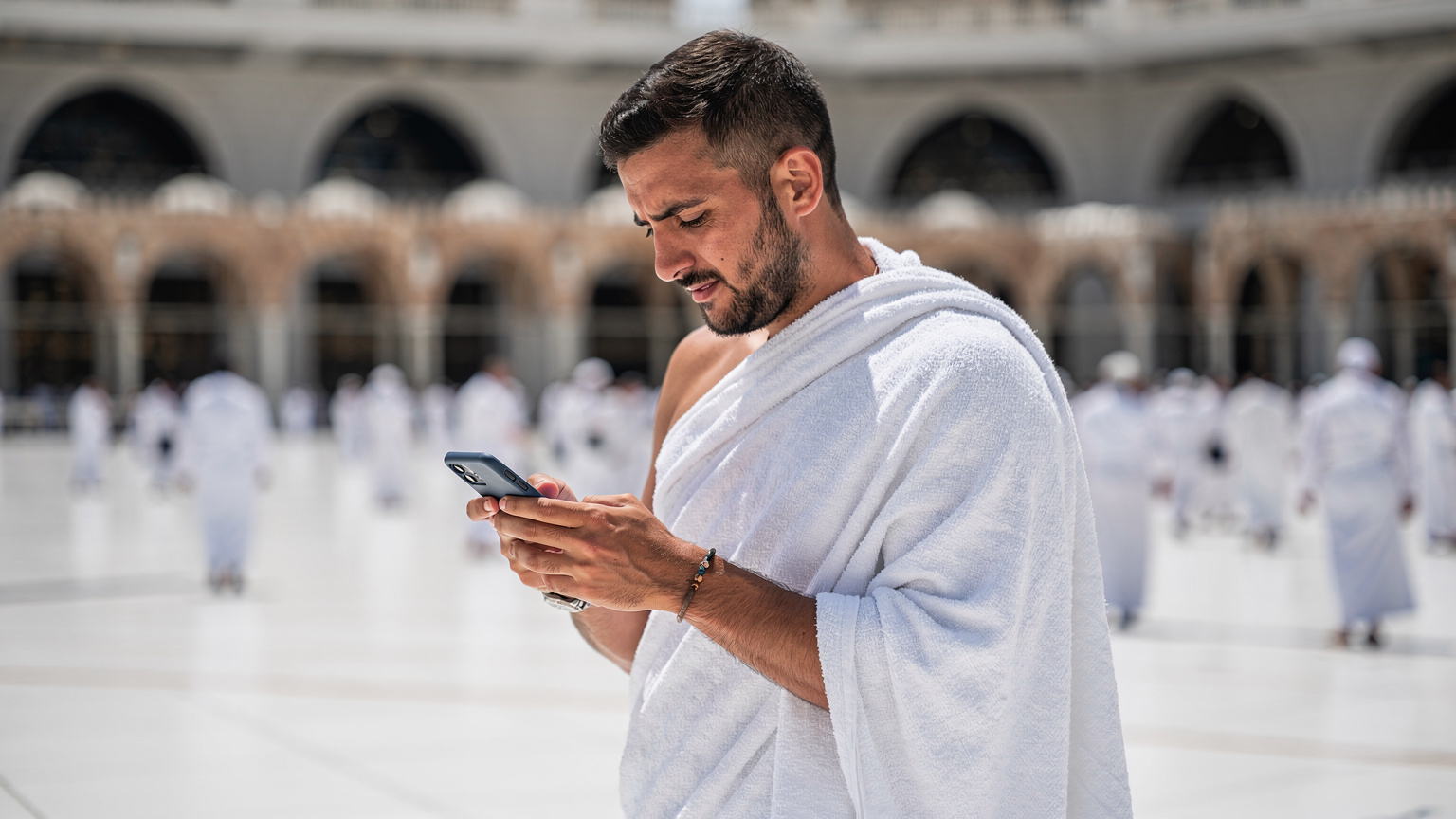 حاج يستخدم هاتفه الذكي لتصفح الخرائط بالقرب من المسجد الحرام في مكة المكرمة.