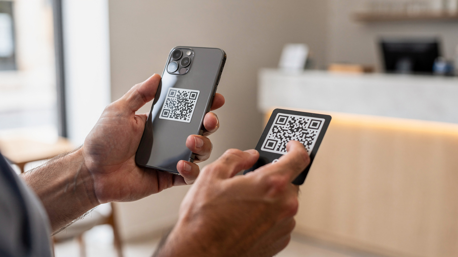 Mãos de um viajante a segurar um smartphone a escanear um QR code para ativar um eSIM, com um fundo desfocado de um balcão de atendimento, simbolizando a facilidade da ativação digital.