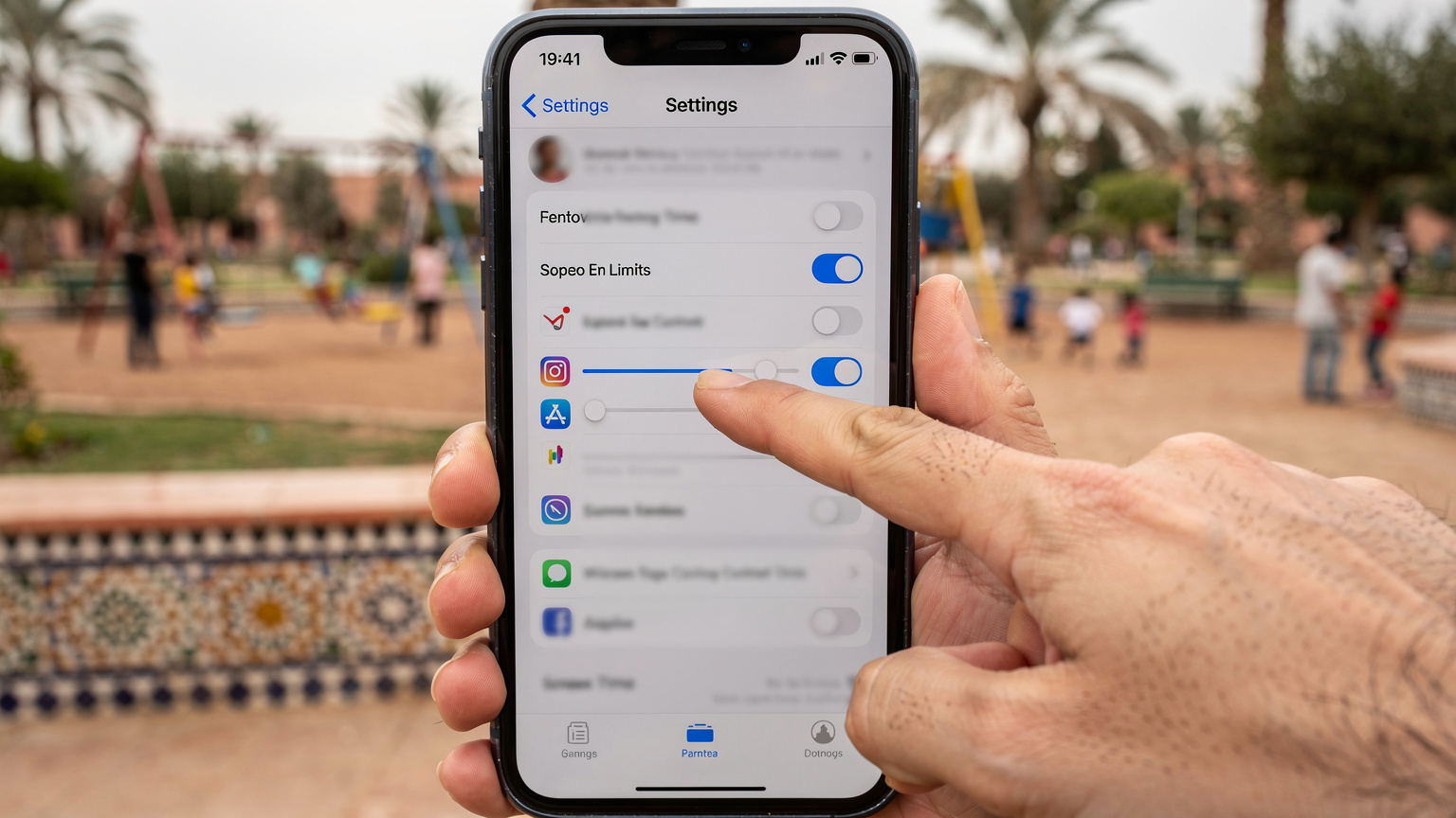 Ein Smartphone-Bildschirm zeigt die 'Bildschirmzeit' oder 'Kindersicherung' Einstellungen, mit Optionen zum Festlegen von App-Limits, während im Hintergrund verschwommen ein Spielplatz in einem marokkanischen Park zu sehen ist, wo Kinder spielen.