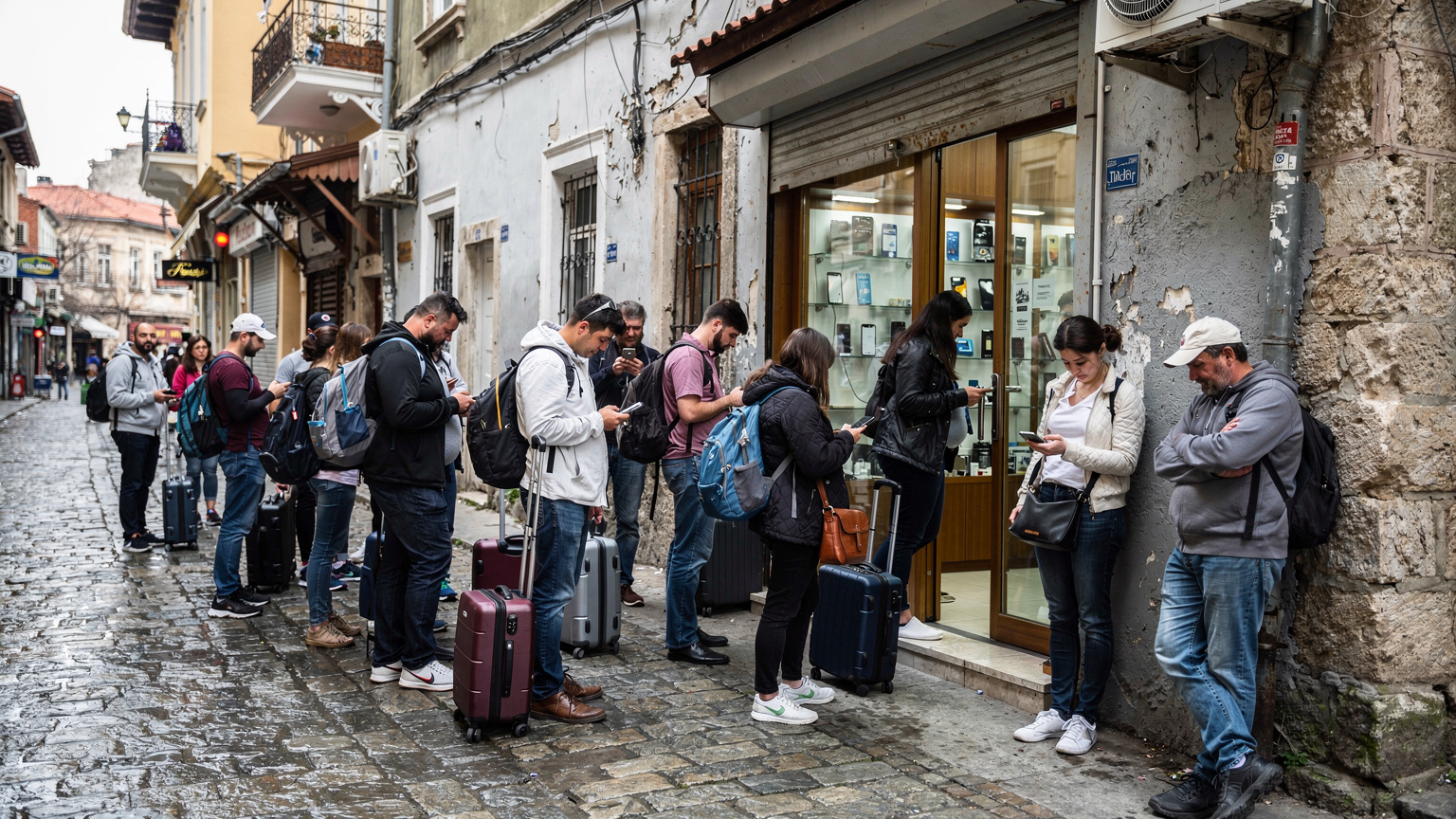 İstanbul'un tarihi sokaklarında bir telefon mağazasının önünde sıraya girmiş turistler.