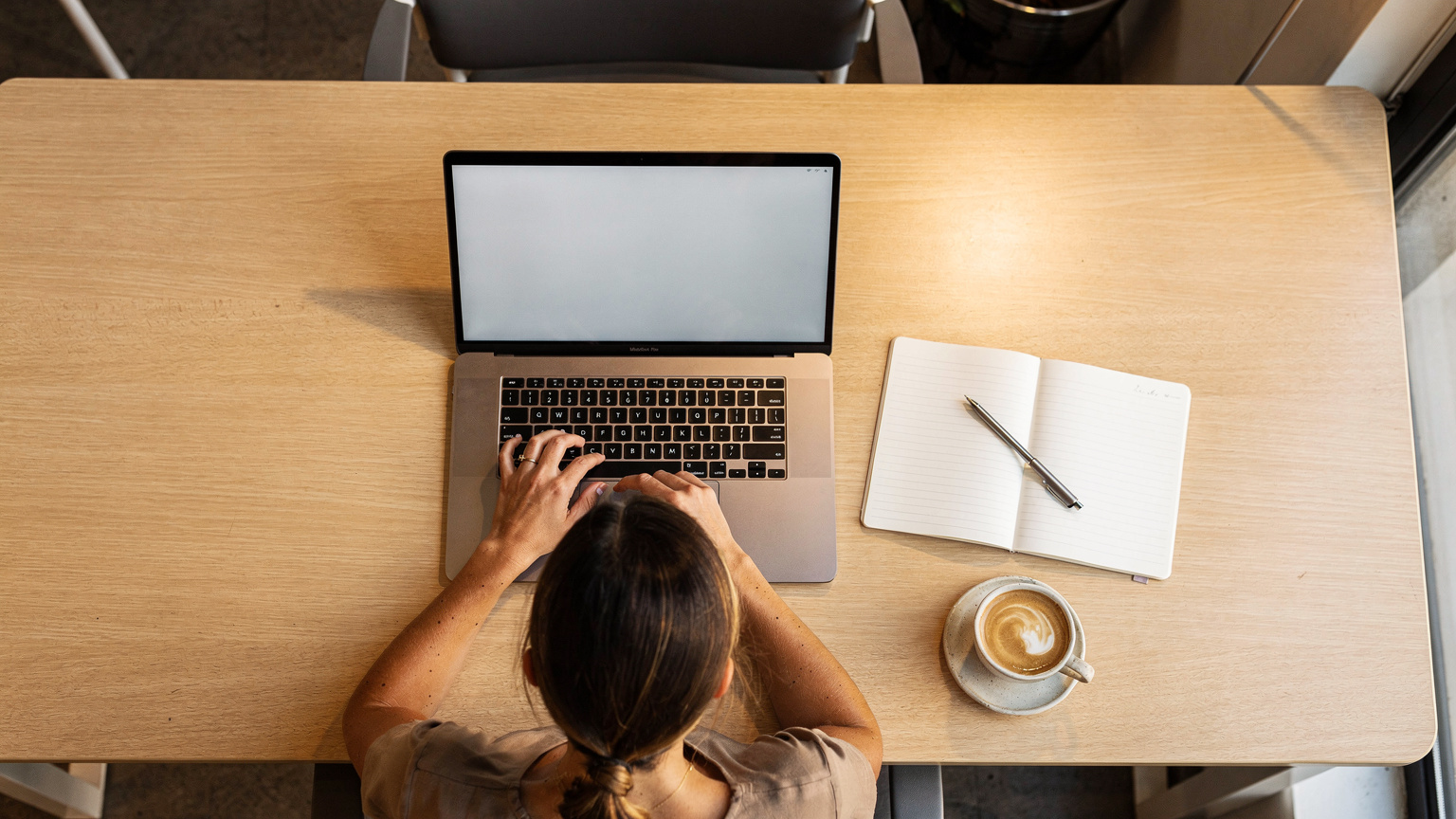 Digitálny nomád v co-workingovom priestore v Lisabone sa snaží kontaktovať zákaznícku podporu na svojom laptope, zatiaľ čo má otvorenú kávu a diár.