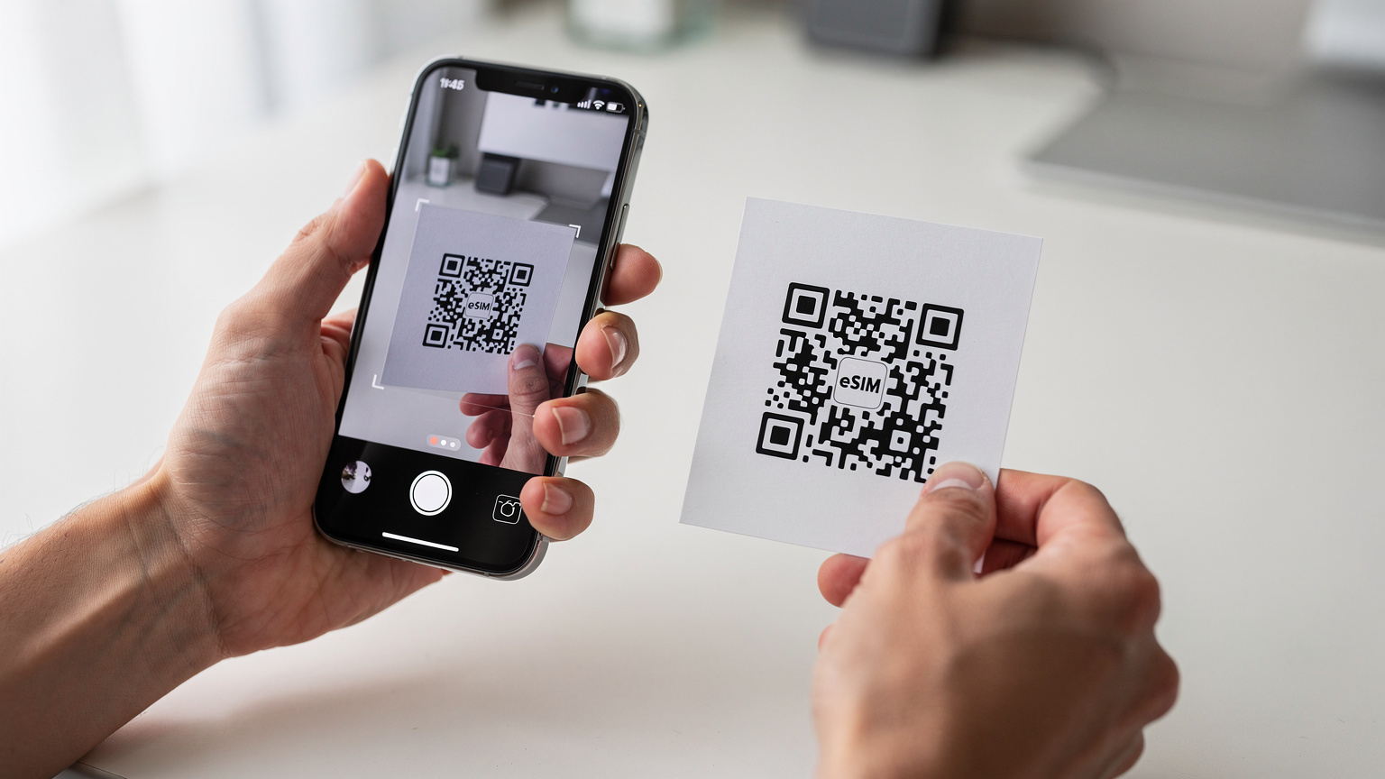 Gros plan sur des mains humaines scannant un QR code d'eSIM depuis un document imprimé vers un nouvel iPhone, dans un environnement lumineux et propre, soulignant l'interaction directe et la facilité d'installation.